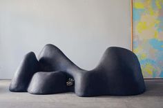 a large blue sculpture sitting on top of a cement floor next to a painting hanging on the wall