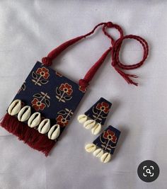 two pieces of fabric with beads and tassels attached to them on a white surface