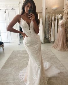 a woman in a wedding dress taking a selfie with her cell phone while looking into the mirror