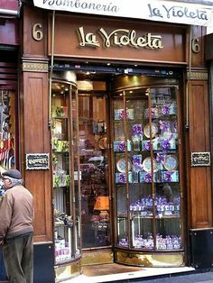 a man standing in front of a store with lots of glass cases on the door