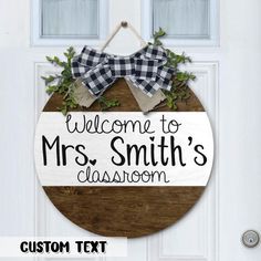 welcome to mrs smith's classroom sign hanging on the front door with wreaths