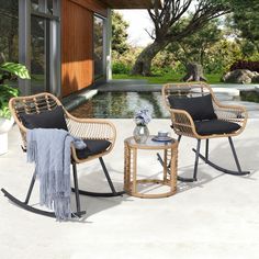 two wicker rocking chairs sitting next to each other in front of a swimming pool