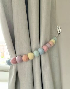 the curtain is decorated with multi colored pom - poms and a metal hook