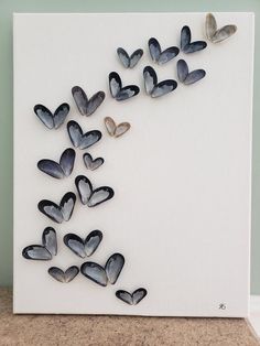 there are many butterflies on the white board with black and silver foiled hearts attached to it