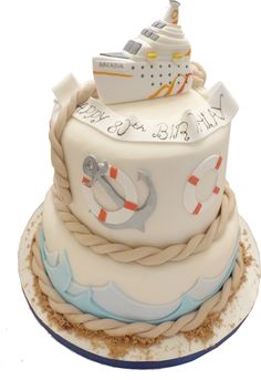 a three tiered cake with a cruise ship on it's side and rope around the bottom