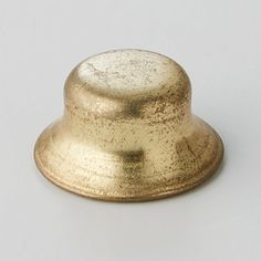 a gold colored metal object on a white surface