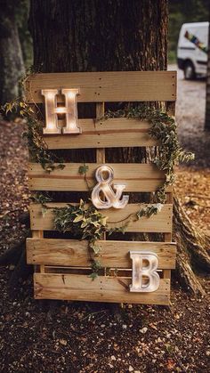 a wooden sign with lights on it that says h and b next to a tree