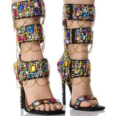 Destined To Be A Pop Culture Icon In The Azalea Wang " Layers Of London " Multi Embellished Sandal! Crafted Using A Satin Textile Upper, These Ornate Sandals Feature An Open Squared Toe Silhouette, A Mid-Calf Shaft Height, A Contrast Metallic Faux Leather Cushioned Insole, A Gemstone Embellished Slim Stiletto Heel, A Gladiator-Style Strappy Design, And A Slim Gemstone Embellished Toe Band. Complete With Colorful, Clustered Gem-Detailing And Cascading Rhinestone Link Accents Adorning The Shaft, A Multicolor Block Heel Sandals For Party, Multicolor High Heel Sandals With Rhinestones, Multicolor Rhinestone High Heel Sandals, Multicolor Open Toe Heels For Party, Bedazzled Sandals For Spring Party, Multicolor Rhinestone Sandals For Spring, Multicolor Embellished Open Toe Heels, Multicolor Crystal Embellished High Heels, Multicolor Crystal Embellished Party Heels