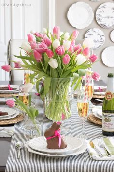 a vase filled with pink tulips sitting on top of a dining room table