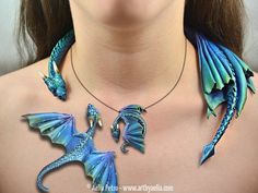 a woman wearing a blue dragon necklace and matching earring with a pendant on her neck