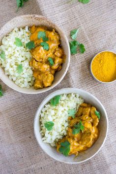 two bowls filled with rice and curry on top of a table next to a spoon