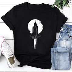 a black t - shirt with an image of a space shuttle flying in the sky