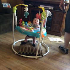 a baby sitting in a swing on the floor