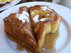 two pieces of french toast sitting on top of a white plate covered in powdered sugar