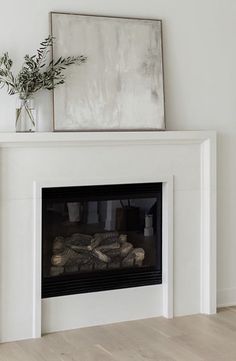 a white fireplace with a mirror above it and a plant on the mantel top