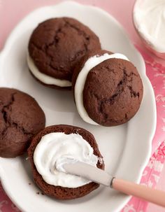 three chocolate cookies with white frosting on a plate