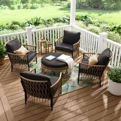 a patio with chairs and tables on the wooden floor next to a white porch railing