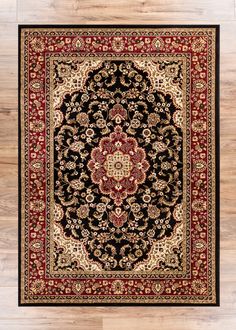 a black and red rug with an ornate design on the center, surrounded by wood flooring