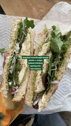 a sandwich with meat, lettuce and onions on it is held in someone's hand