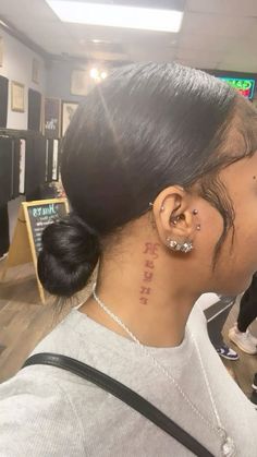 a woman with piercings on her ear and behind her ear is a sign that reads,