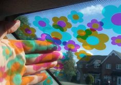 someone is holding their hand out the window with colorful flowers on it and houses in the background