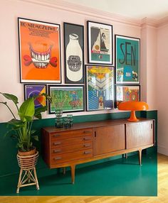 a living room with posters on the wall and a wooden dresser in front of it