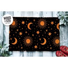 a black rug with orange stars and moon on it, next to red booties