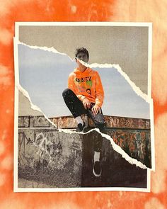 a young man sitting on top of a skateboard next to a graffiti covered wall