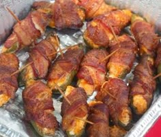 bacon wrapped jalapenos sitting on top of aluminum foil in a pan with toothpicks sticking out of them