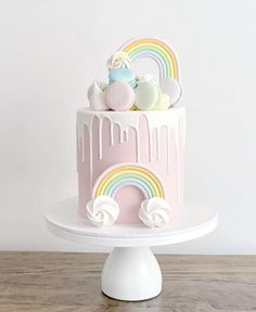 a pink cake with white icing and rainbow decorations