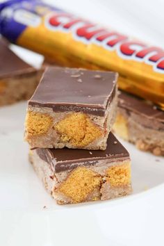 three pieces of chocolate peanut butter bars on a white plate with a bar in the background