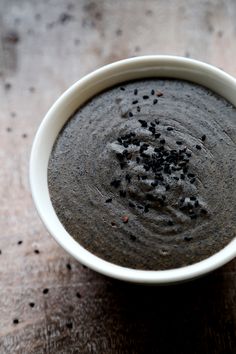 a white bowl filled with black food on top of a wooden table