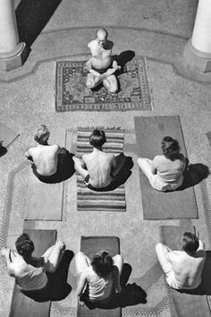 several people sitting in yoga mats on the floor with their backs turned to one another