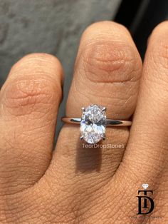 a woman's hand with a diamond ring on top of her finger, showing the center stone