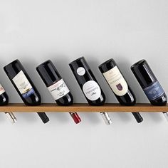 a row of wine bottles sitting on top of a wooden shelf