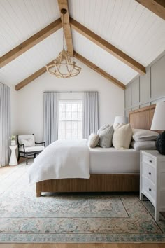 a bedroom with white walls and wood beams