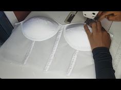 a person working on an object with white fabric and buttons in the shape of bras