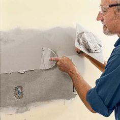 an older man is painting the wall with gray paint