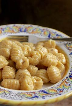 a white plate topped with macaroni and cheese covered in gravy next to a fork