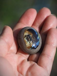 a hand holding a small rock with a man in it