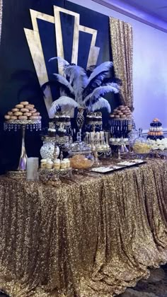 a table topped with lots of desserts covered in gold sequins and feathers