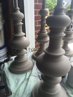 some very large vases on a table by a brick wall in the day time