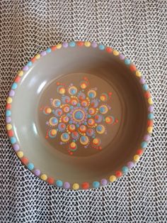 a brown bowl with multicolored polka dots on the bottom and an orange flower in the center