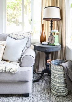 a living room filled with furniture and a lamp on top of a table next to a window