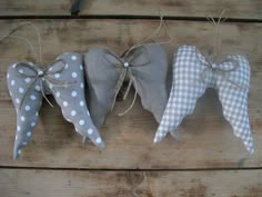 three fabric angel ornaments tied together with twine on wooden planks, one in white and the other in grey