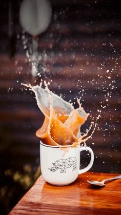 an orange splashing into a white coffee cup