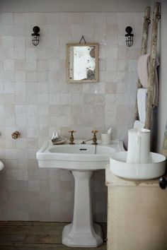 a white pedestal sink sitting under a mirror in a bathroom next to a wooden pole