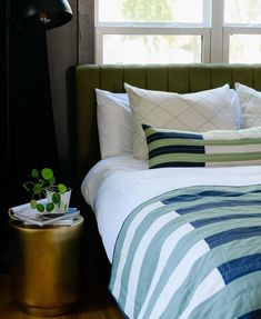 a bed with white and blue sheets in front of a window