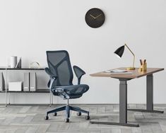 an office chair and desk with a clock on the wall above it, in front of a table