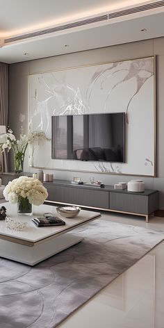 a modern living room with white furniture and flowers on the coffee table in front of the flat screen tv